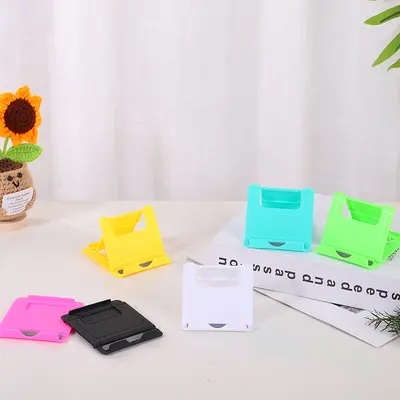 Kreativer fauler Desktop-Telefonständer des Herstellers, einfacher zusammenklappbarer Kunststoff-Telefonständer, Großhandel Geschenkartikel, bedruckbar mit LOGO.